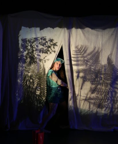Une personne cachée derrière un rideau blanc avec des ombres chinoises en forme de plantes sauvages